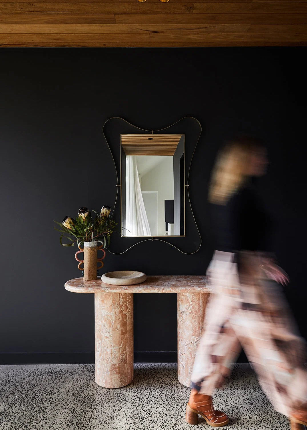 Entryway design in Wallington with black wall, timber batten ceiling, and marble console table styled with Rachel Donath arte mirror and decor by Nikki McGar Interiors.