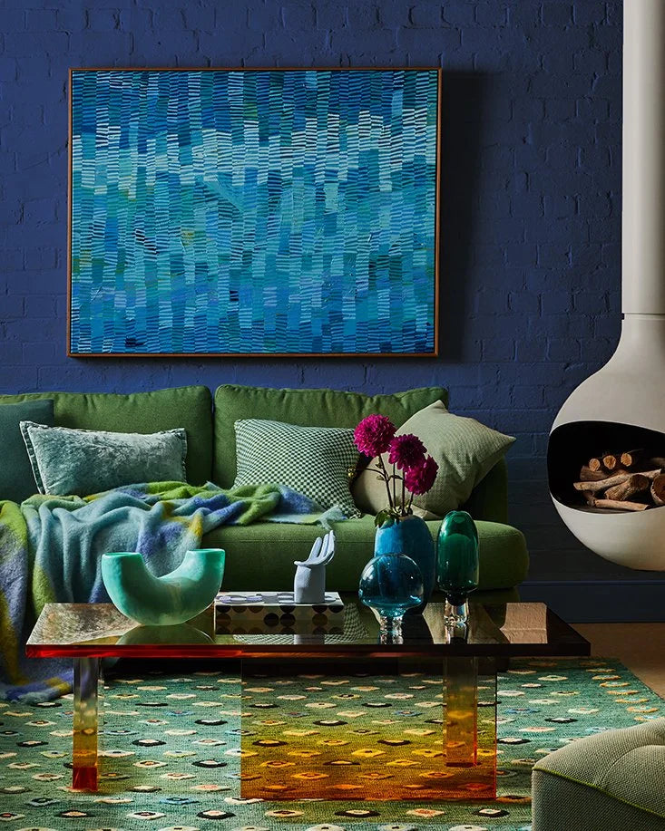 Modern living room design with blue walls, green Molmic sofa, statement art, and Oblica fireplace
