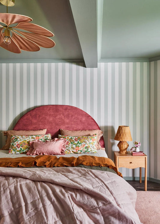 Playful airbnb bedroom featuring custom curved headboard and green striped wallpaper designed by Nikki McGar Interiors.