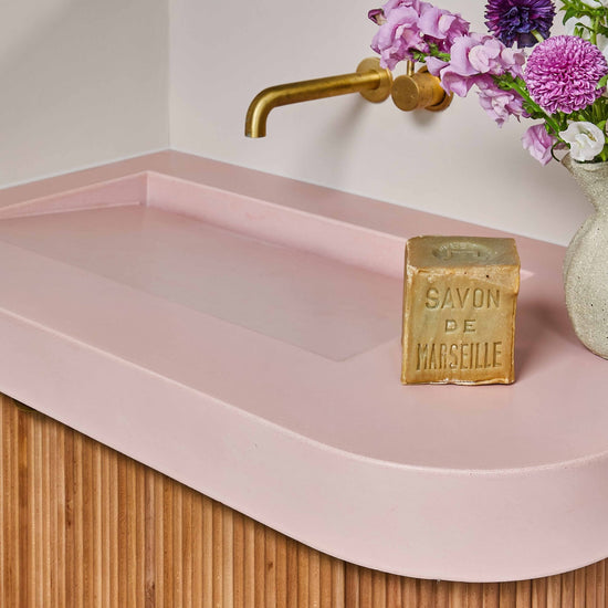 Barwon Heads bathroom renovation featuring custom pink concrete sink, brass fittings, and contemporary styling by Nikki McGar Interiors.