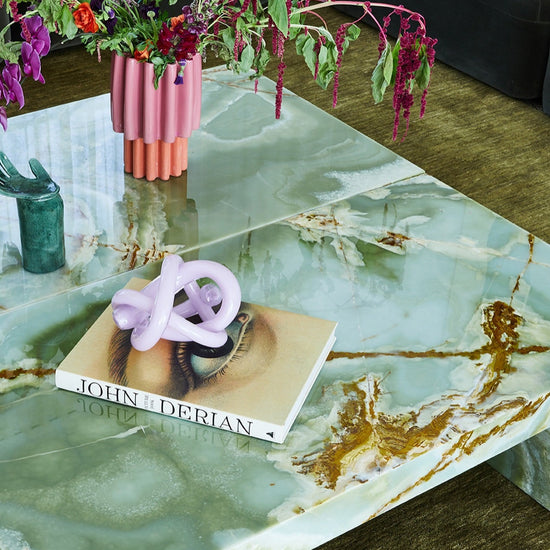 Close-up of green marble coffee table with decorative styling by Nikki McGar Interiors on green rug