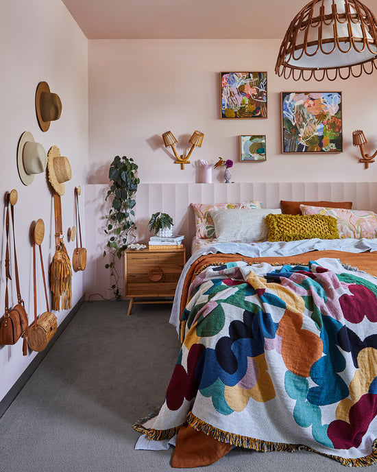 Bedroom renovation by Nikki McGar Interiors featuring a built-in bedhead, wall hooks for extra storage and rattan wall light for a natural, coastal-inspired look.