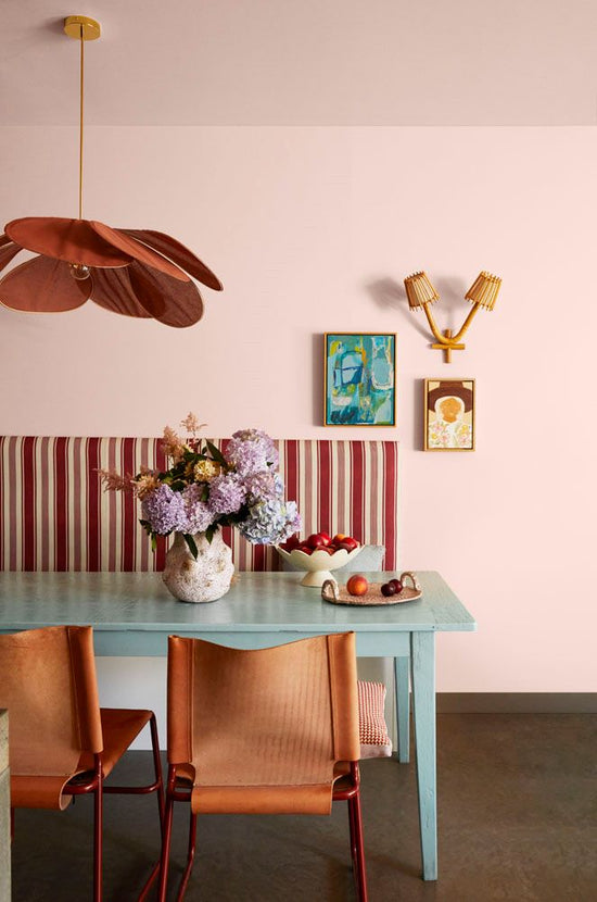 After: Barwon Heads dining area designed by Nikki McGar Interiors featuring a custom Warwick Fabric banquette in striped burgundy and pink tones, french petal pendant light, dowel jones chairs