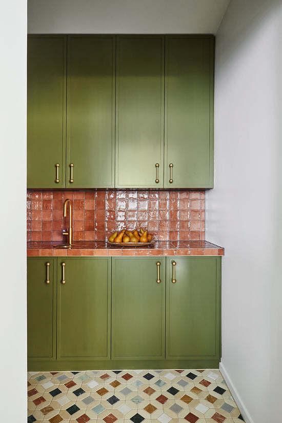 After: Butler’s pantry renovation in Newtown by Nikki McGar Interiors featuring green cabinetry, tiled bench, and brass fixtures for a cohesive extension of the main kitchen.