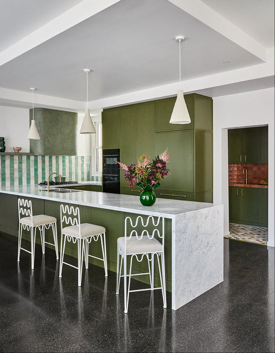 Family kitchen in Newtown featuring deep green cabinetry, rachel donath stools, andstriped tiled splashback by Nikki McGar Interiors.