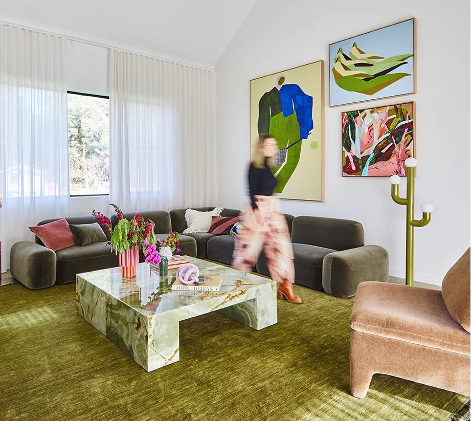 Modern living room with a green rug, green sofa, and colorful large scale artwork on the wall.