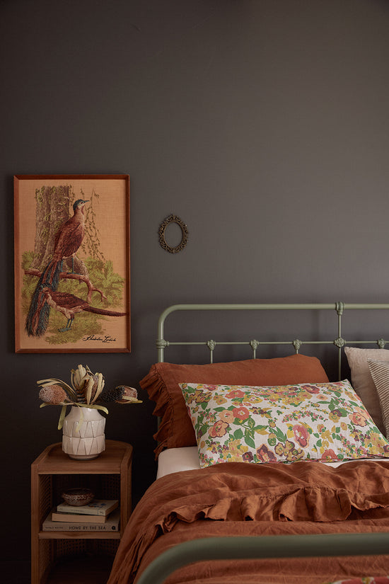 After: Merimbula Airbnb bedroom designed by Nikki McGar Interiors featuring a vintage artwork and relaxed holiday styling.