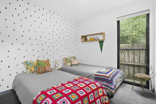 Before: Kid’s bedroom prior to renovation by Nikki McGar Interiors, with plain white walls and minimal storage.