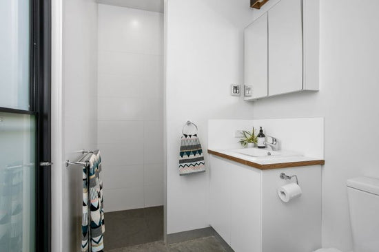Before: Original Barwon Heads bathroom prior to renovation by Nikki McGar Interiors, with plain white tiles and minimal colour.