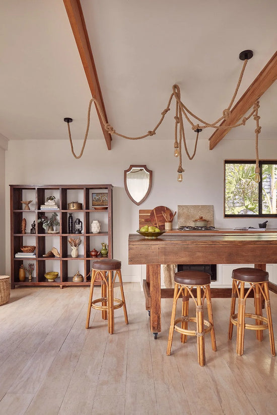 Warm, rustic kitchen transformation in a coastal Tree House featuring timber textures, vintage details, and a repurposed carpenter’s workbench island by Nikki McGar Interiors.